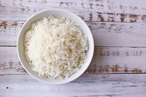 The bowl of cooked rice photo on wooden background top view copy space