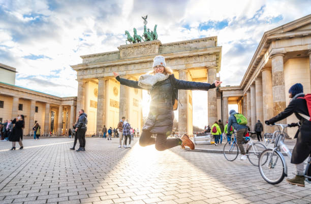 joven saltando frente a la puerta de brandeburgo en berlín - berlin germany brandenburg gate germany monument fotografías e imágenes de stock
