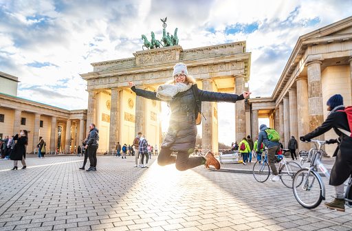 Young woman jumping in front of Brandeburg Gate in Berlin