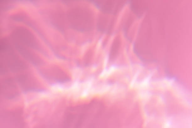 Beautiful lights and shadows of glass on pink or purple background. Overlay mode. Caustic effect of light. Sun hard reflection. Shadows texture. Blurred water backdrop. Top view. Trendy concept