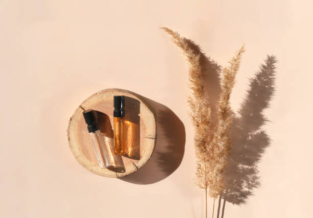 istock Two Glass perfume testers with brown liquid on a woodcut with pampas grass. Top view 1394165934