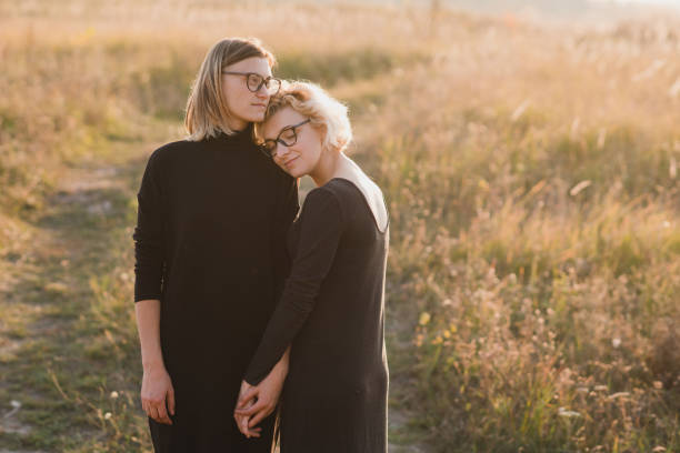 mujeres jóvenes y elegantes abrazándose al atardecer, cariñosas y felices. - multi ethnic group couple sex women fotografías e imágenes de stock