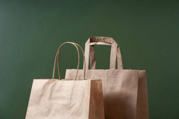 クラフト紙は、緑の背景の最小限のコンセプトにショッピングバッグをリサイクルしました。持続可能な包装コンセプト。 - paper bag bag brown handle スト�ックフォトと画像