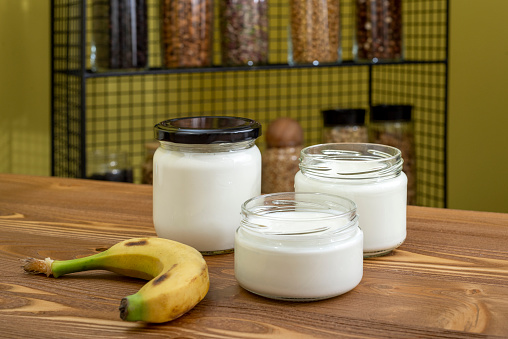 Yogurt in glass jar on a wooden background. Kefir, banana.