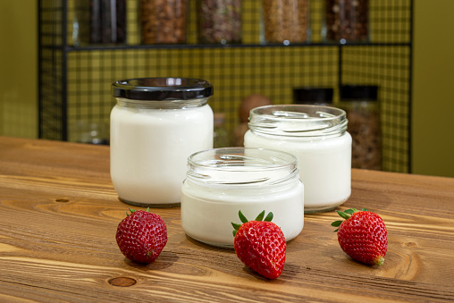 Yogurt in glass jar on a wooden background. Kefir, strawberry