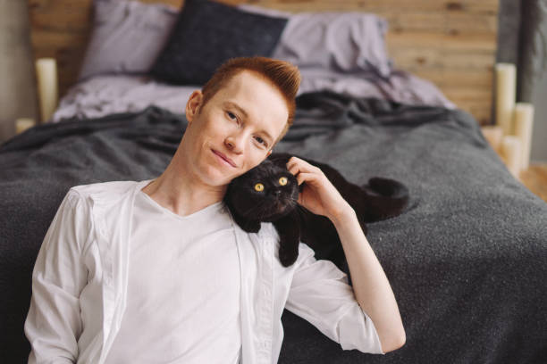 istock Happy young handsome caucasian man sitting with a black cat. 1394171192