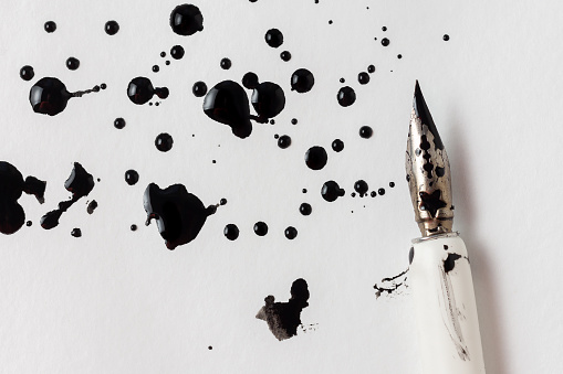 Ink blots and a fountain pen on a white sheet of paper