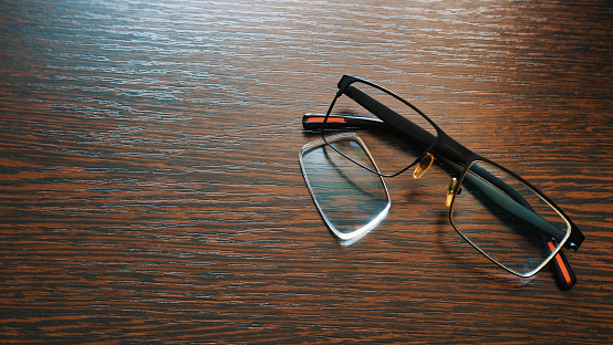 Glasses with a fallen out lens on a wooden surface
