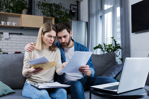 Man and woman, young family together intently reading a letter, frustrated