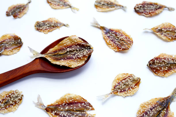 Dried fish with sesame seeds on white background.