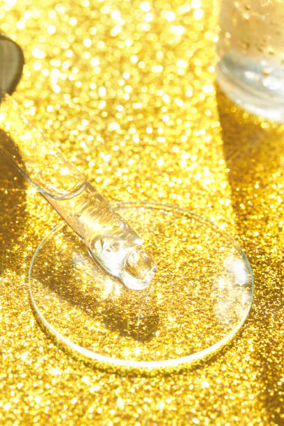 istock Serum gel texture swatch. Transparent drop with golden sparkles with bubbles 1394178346