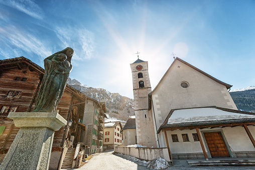 Vals, Switzerland - March 13, 2021: Vals is a mountain village in the Swiss Alps. It is situated in a remote location in the canton of Graubünden. Vals is famous for its mineral spring water. On the picture the town square with houses and church.