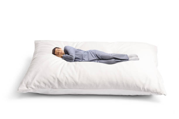 istock Young man in pajamas sleeping peacefully on a big pillow 1394194287