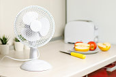 A small fan on the kitchen table. The concept of cooling and ventilation of the house.