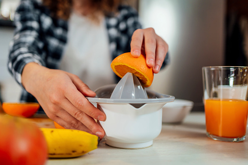 Woman preparing fresh orange juice in the kitchen