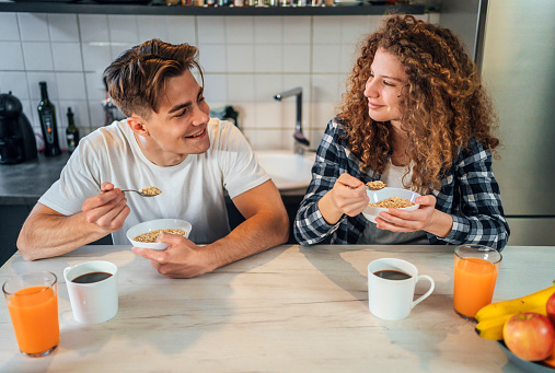 Young cheerful couple eating cereal breakfast in the kitchen at home