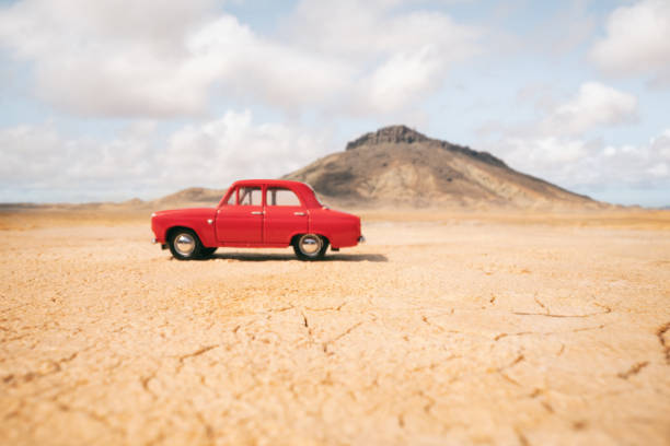 A small old-fashioned car sitting in a vast open desert.