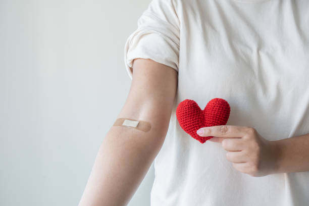 Blood donation concept. Give blood save up to three lives. Blood donation concept. Give blood save up to three lives. Woman arm with the bandage plaster showing as a blood donation volunteer. blood test stock pictures, royalty-free photos & images