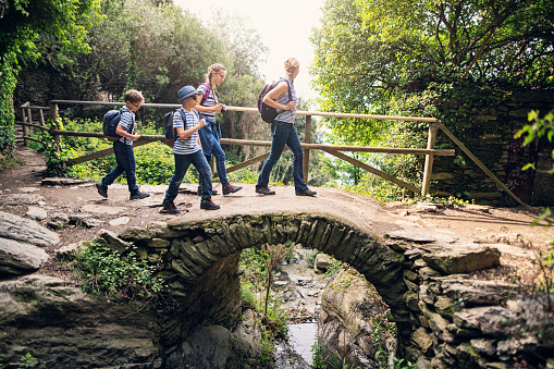 Family hiking in trails of Cinque Terre - a UNESCO World Heritage Site. The family walking on a trail from Vernazza to Monterosso al Mare. They are walking over a small cute arch bridge over a stream.
Nikon D850