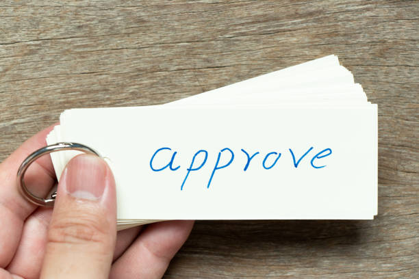 istock Man hold the flash card with handwriting word approve on wood background 1394209780