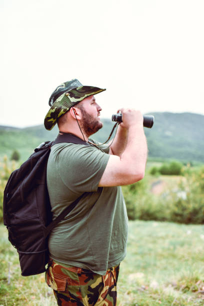 istock Side View Of Bearded Overweight Hiker Looking At View Through Binoculars 1394213620