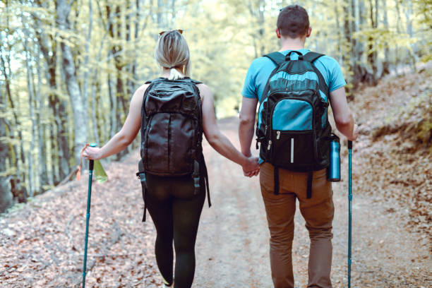 istock Rear View of Cute Couple Holding Hands While Walking On Forest Footpath 1394213690