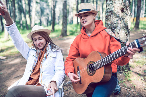Two Cute Females Having Party In Forest With Guitar While Camping