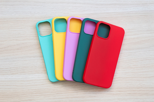 Cases set for smartphone on wooden background. Silicone protection for mobile phone. Colorful silicone phone cases.