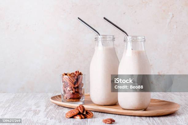 Pecan Milk In Glass Bottles With Reusable Metal Drinking Straw Stock Photo - Download Image Now