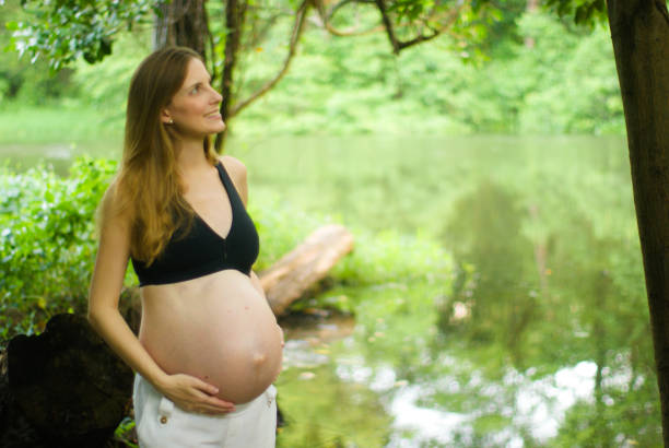 Portrait of happy young pregnant woman walking in sunny summer day