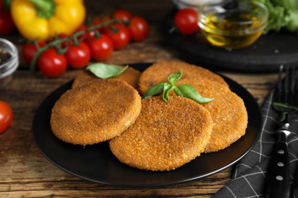 istock Delicious fried breaded cutlets with basil on wooden table, closeup 1394223401