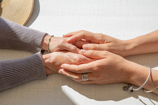 Young woman embraces her mother's hands