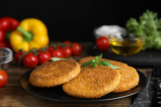 istock Delicious fried breaded cutlets with basil on wooden table, closeup 1394225780