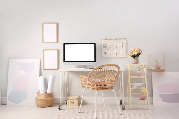 istock Comfortable workplace with modern computer and flowers in room. Interior design 1394226001