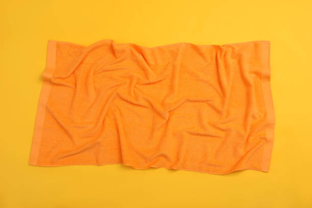 istock Crumpled orange beach towel on yellow background, top view 1394228810