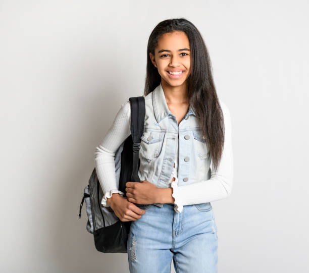 istock Beautiful black school girl posing on studio white background with backpack 1394229644