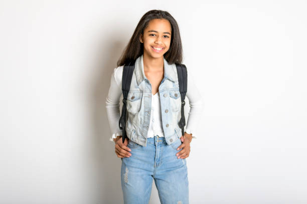 istock Beautiful black school girl posing on studio white background with backpack 1394229697