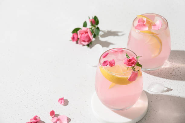 nalewając różowy koktajl alkoholowy z kwiatami róży na białym tle. - flower drink zdjęcia i obrazy z banku zdjęć