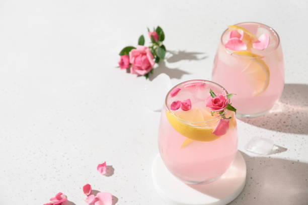 derramando coquetel alcoólico rosa com flores de rosa no fundo branco. - flower drink - fotografias e filmes do acervo