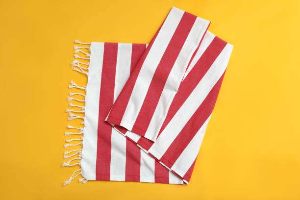 Folded striped beach towel on yellow background, top view