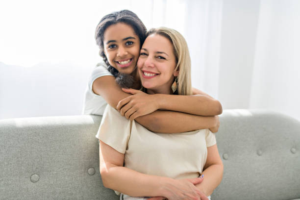 母親と愛らしい黒人の十代の娘が自宅のソファに座っている - family single mother black mother ストックフォトと画像