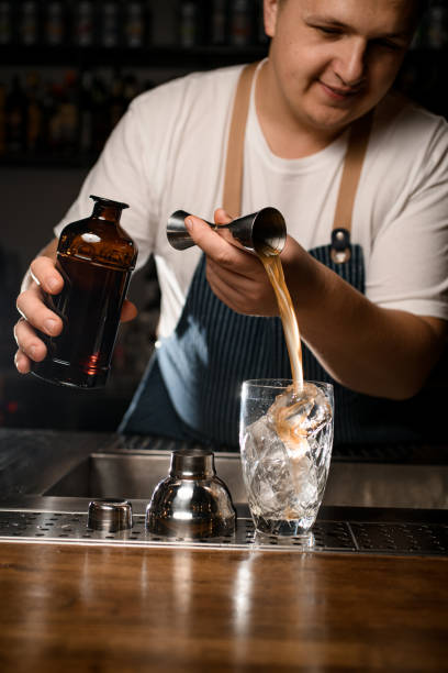 istock Male bartender pours liquid from jigger into crystal mixing cup 1394230179