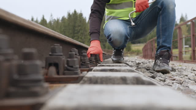 Worker tightens the screw on railroad. Engineer walking and check track work on railways. Inspection and control of railway tracks is carried out by the engineer. Work on railway