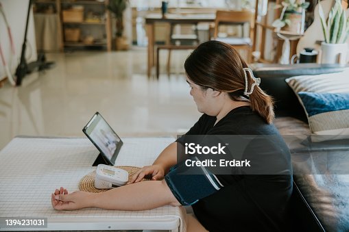 istock Telemedicine, Asian plus size woman checking her blood  and heart rate pressure by herself at home. 1394231031