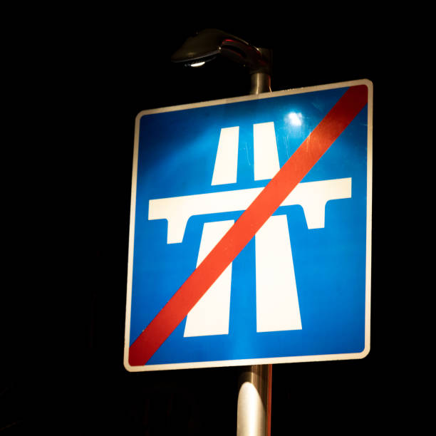A UK sign for the end of a motorway, illuminated at night.
