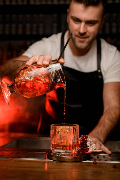 istock bartender gently holds a mixing cup with a strainer and pours liquid into whiskey glass 1394233157