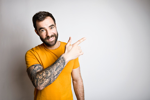 A portrait of casual young man with beard and tattoo and Burnt Orange shirt on white background
