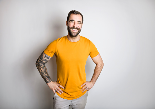 A portrait of casual young man with beard and tattoo and Burnt Orange shirt on white background