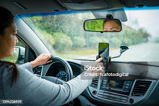 istock Using smartphone while driving car in a rainy day 1394236939