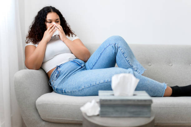 istock Sick ill black woman with tissue sitting on sofa 1394239100
